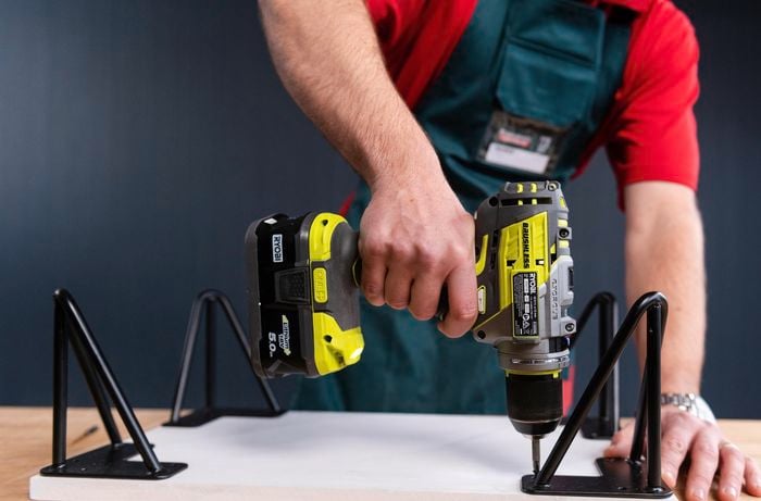 Bunnings team member drilling in hooks with a drill into the timber board