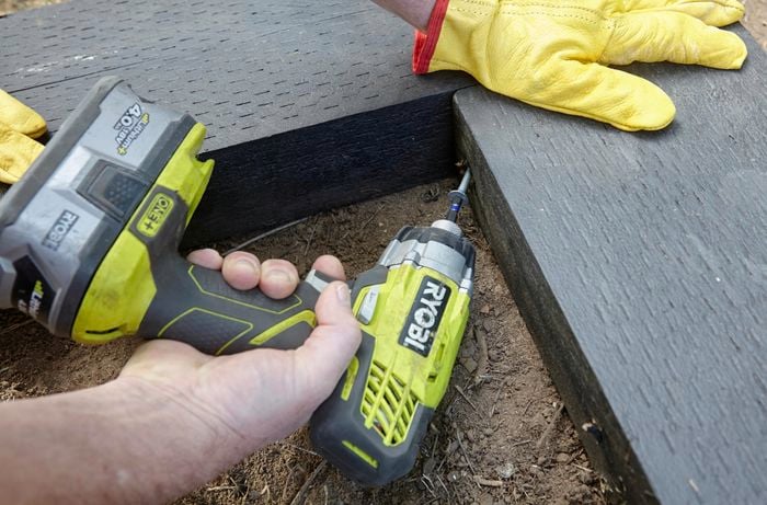A person joining two sleepers at right angles using a cordless drill