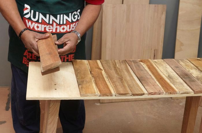 Person laying out timber slats on a workbench