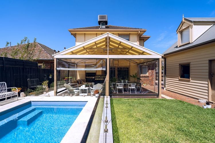 Backyard of house with lawn, pool and covered timber decking area