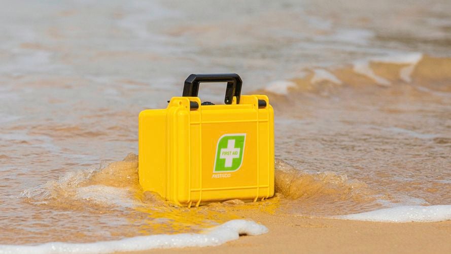 FastAid Essentials IP67 Waterproof First Aid Kit With Yellow Plastic Case in the water at the beach
