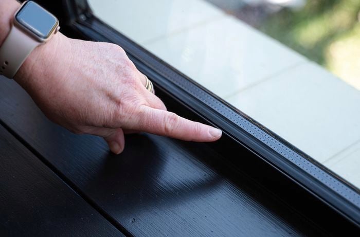 A person pointing his finger to a window rubber seal.