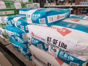 Stacks of large BT-SF Lite and BT-450 tile adhesive bags arranged on pallets inside a warehouse.