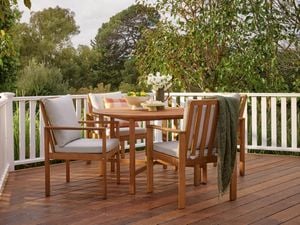 round timber table sitting in decking with white balustrade