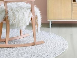 White circular rug and chair with white fluffy shag rug.