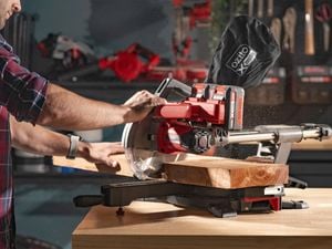 A person using a circular saw to cut a piece of timber.