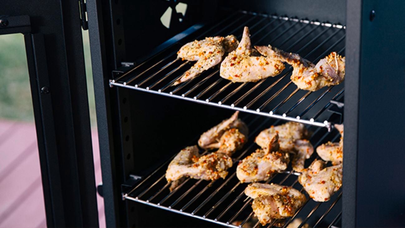 Raw chicken on racks in smoker.