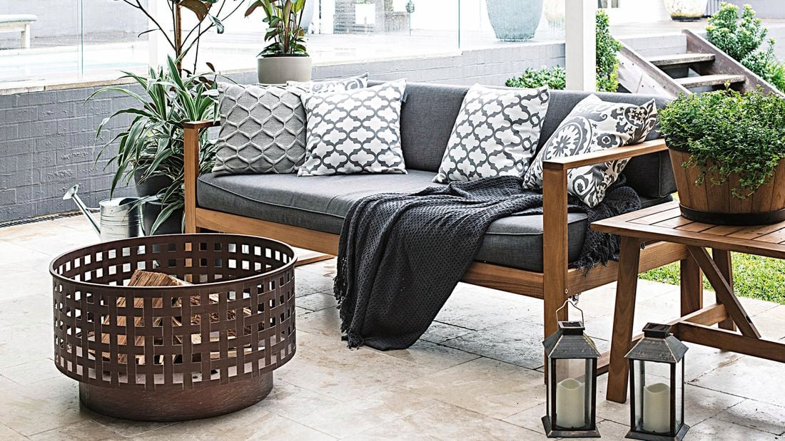 A paved outdoor room with a couch and fire drum