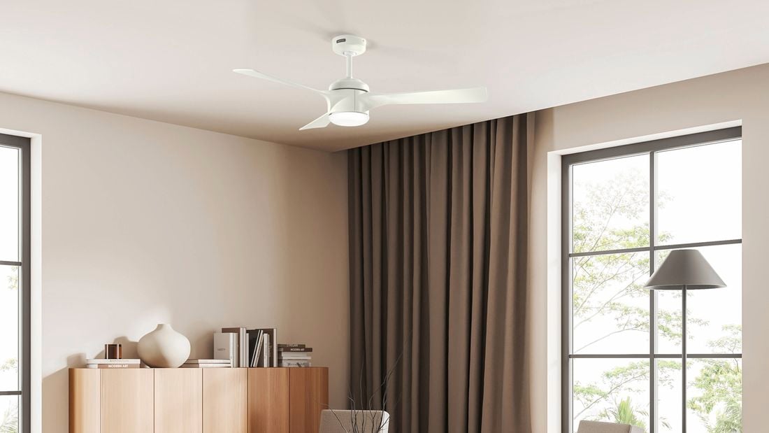 A white Rosedale ceiling fan with a light is installed in a modern room with large windows, curtains and a wooden cabinet.]    Caption: Choose the right Hunter ceiling fan for your home to make staying cool a breeze. 