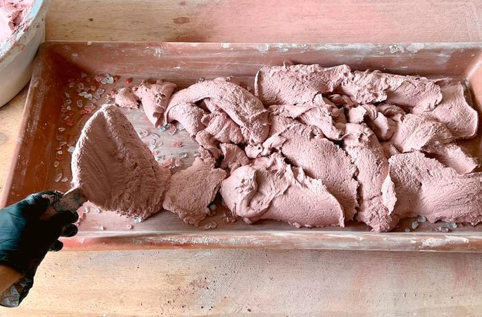A person fills a mould with a pink terrazzo cement