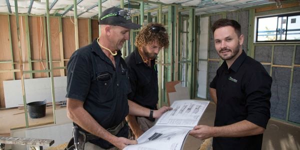 a couple of men in a working space looking at camera
