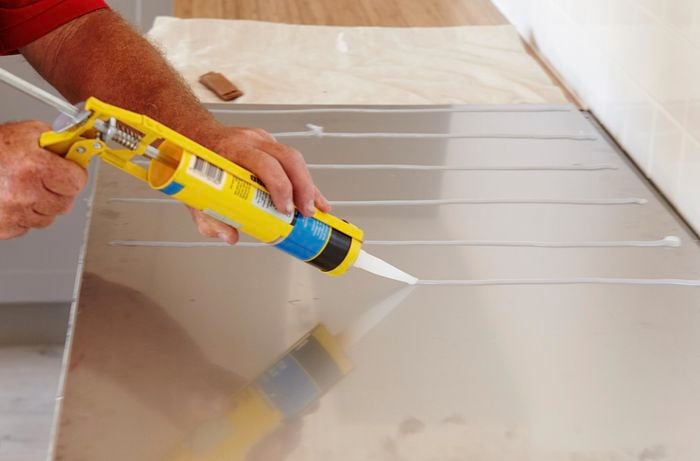 Silicone being applied to the back of a stainless steel splashback