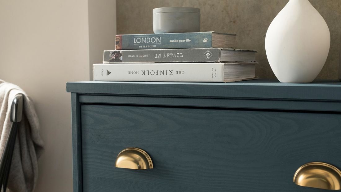 Newly fitted brass handles on a teal chest of drawers in a neutral living room setting