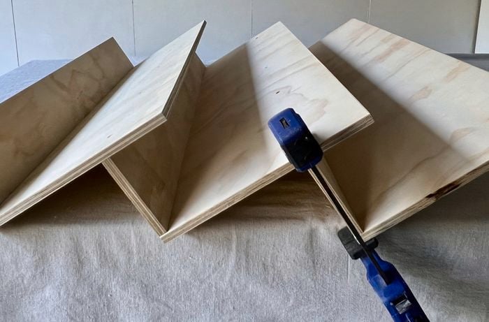 Wooden pallets sitting as a shelf, held by a navy blue clamp