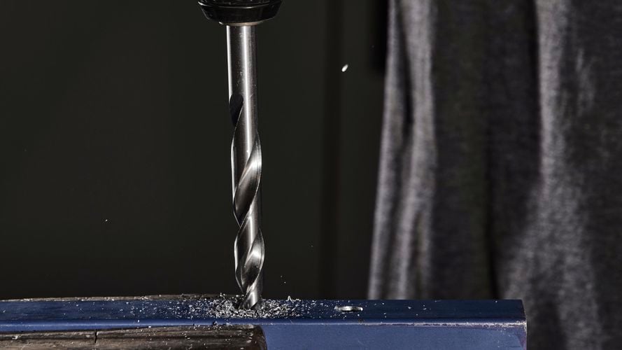 Drill machine drilling hole into metal.
