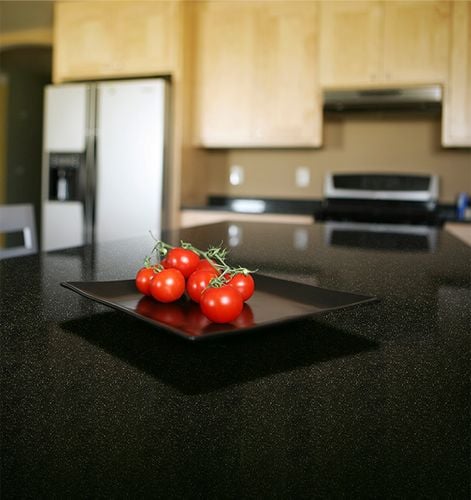 Close up of a black speckled benchtop with a plate of tomatoes
