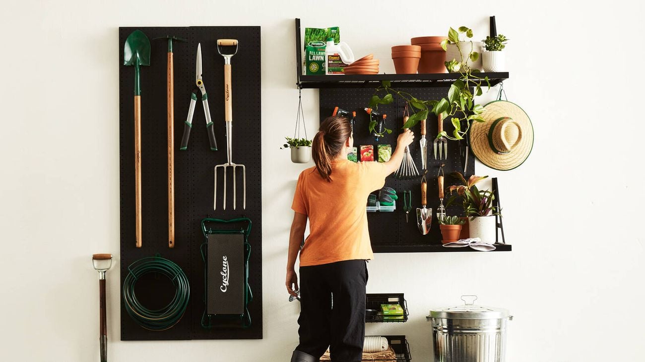 Wall-mounted pegboards with shelves and baskets for gardening tools and supplies