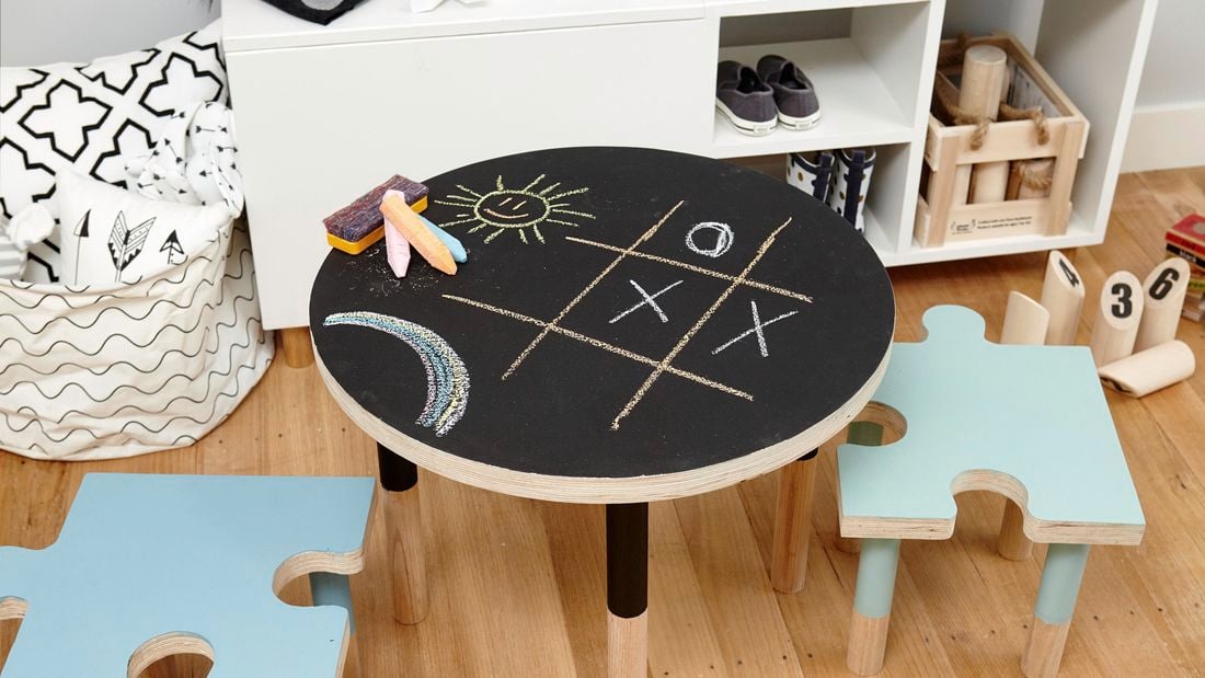 A round chalkboard table with chalk and children's drawings