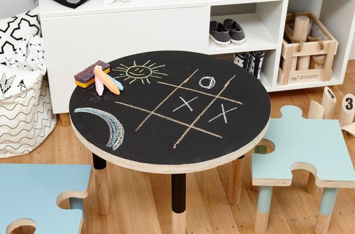 A round chalkboard table with chalk and children's drawings
