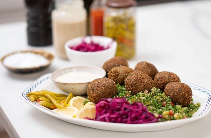 Falafel balls alongside refreshing tabouli salad, accompanied by lemons and yellow chilies.