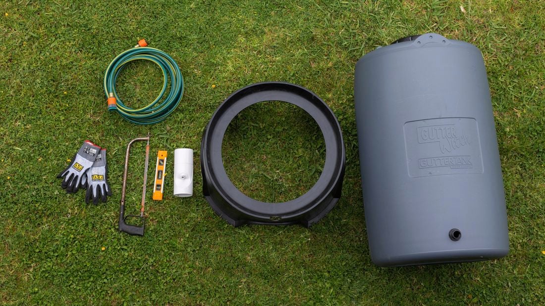Tools and materials for installing a rainwater tank laid out on the grass.