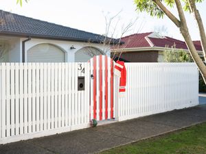 Finished white fence with a red striped gate, scarf and football decorating the entrance.