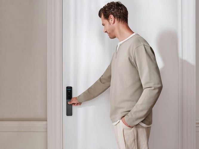 Person using fingerprint scanner on a Philips Smart Lock installed on a front door.