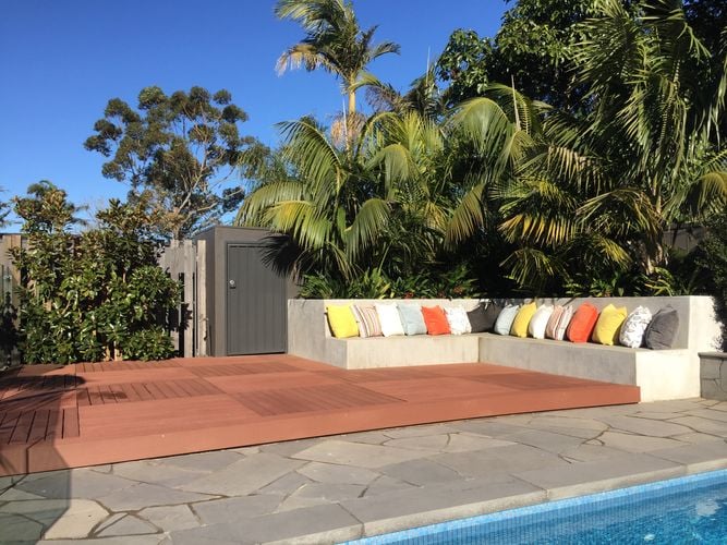 Outdoor deck area with concrete seating area next to a pool