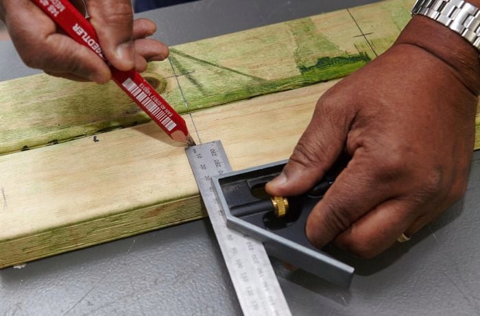 A square rule being used to mark pieces of timber