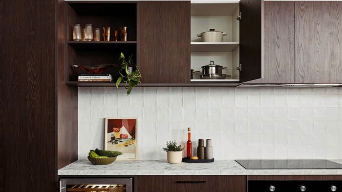 Brown modern kitchen with Marble benchtops with crockery on it and an oven in it.
