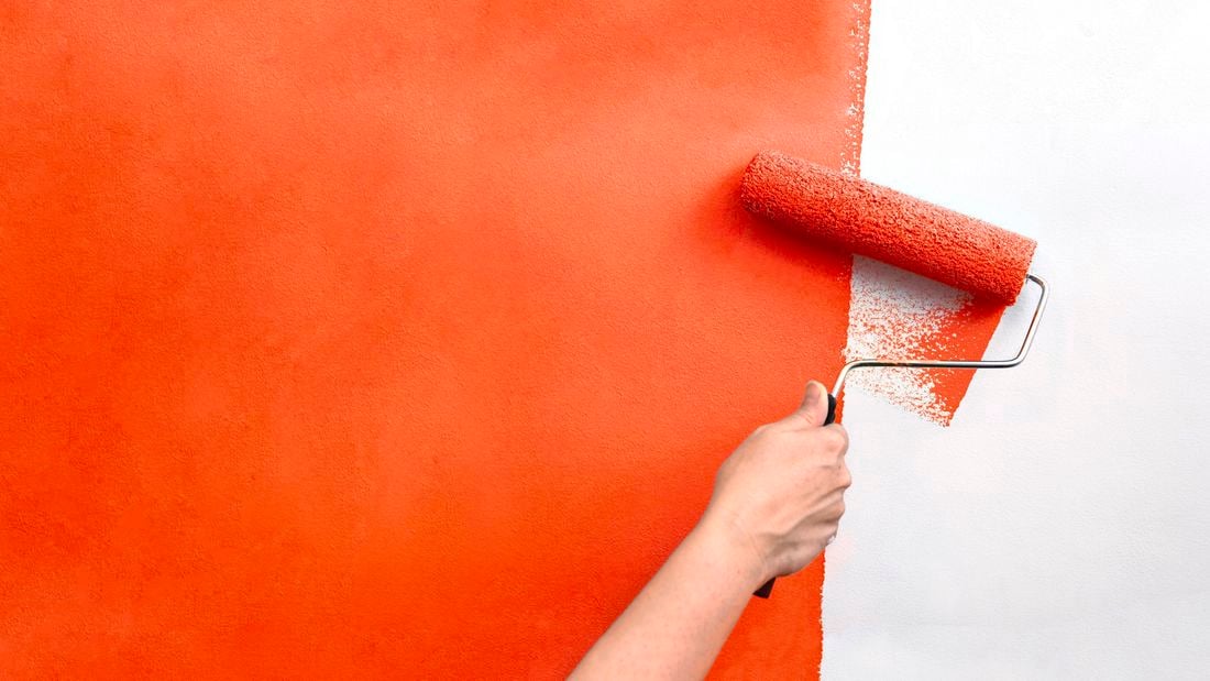 A wall being painted orange with a paint roller
