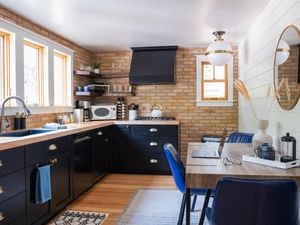 A vibrant white and blue themed kitchen with bare bricks and wooden panelling