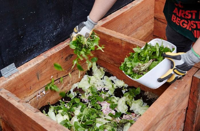 A Bunnings team member adding garden scraps and clippings to a completed sleeper compost bin