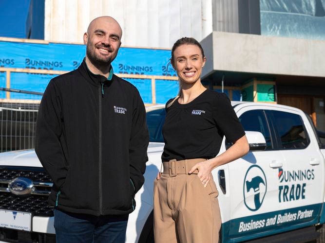 2 people posing in front of a building site with a bunnings trade ute also in shot