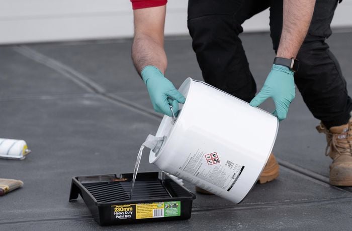 A Bunnings team member using a white bucket, mop and paint tray