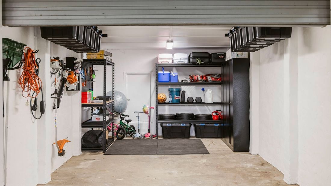 Completed garage makeover with organised shelves, ceiling storage tubs and wall-mounted tools.