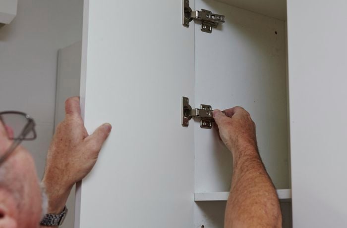 Push to open hinges being fitted inside a kitchen cabinet