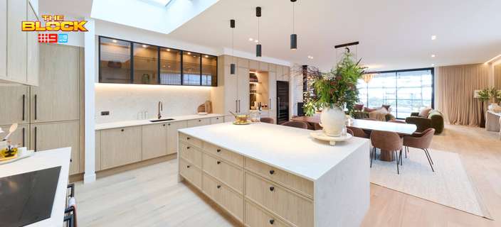 Modern open-plan kitchen and dining area featuring a large island bench, light timber cabinetry, pendant lighting and skylights.