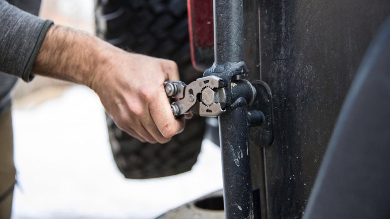Person holding a Gerber Dual-Force with one hand, using the pliers function to turn a bolt on a car.