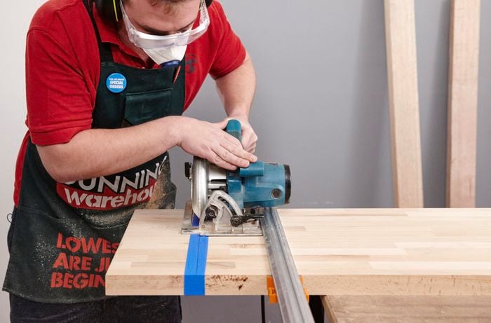 Person using circular saw to cut piece of timber to length.