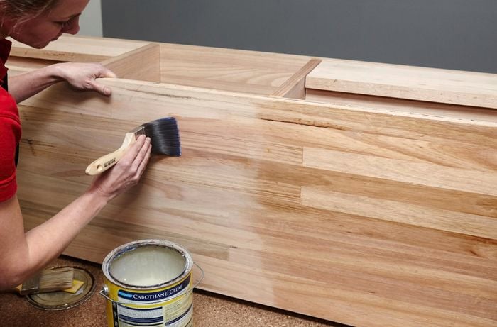 A person applying clear sealer to a timber vanity unit