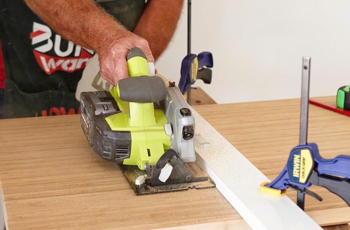 Person using saw to cut through bamboo benchtop.