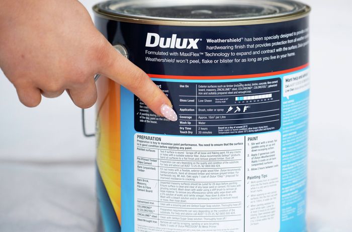 Person checking the paint type before cleaning brushes and rollers
