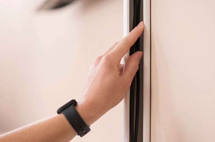 A hand arranging cables into the adhesive cable cover.