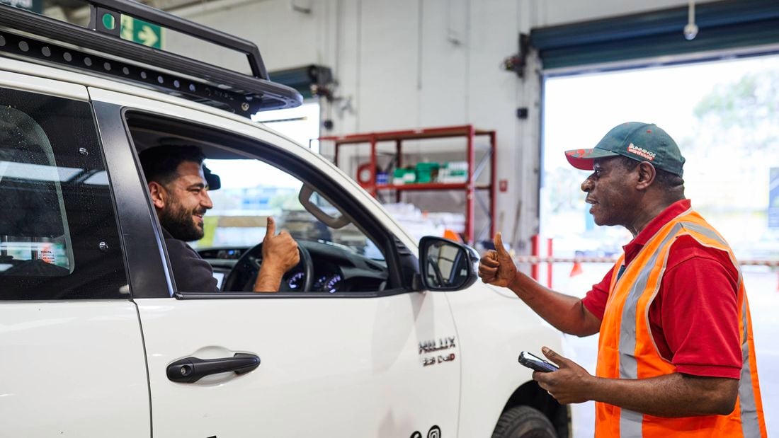 A Bunnings Warehouse team member and a tradie in a white ute give the thumbs up to each other