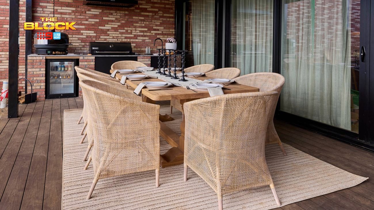 An outdoor area with a table and chairs around it in front of a barbecue.