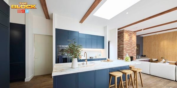 Kitchen with navy island, marble top, wooden stools, and open-plan living.