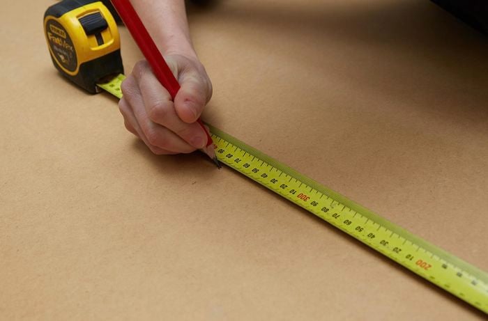 Person marking timber with tape measure and pencil