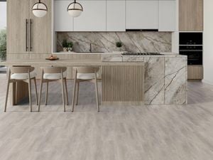 Modern kitchen with vinyl flooring, light wood cabinetry, a large island with seating, marble splashback and pendant lights.