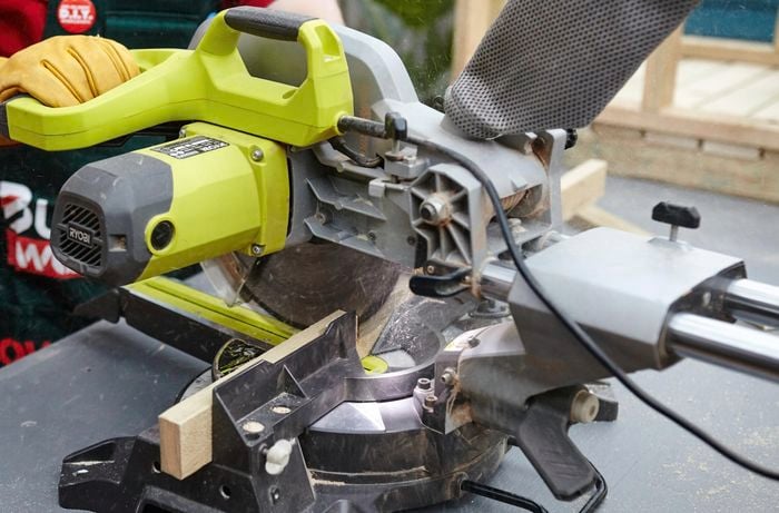 Person using circular saw to cut piece of timber.
